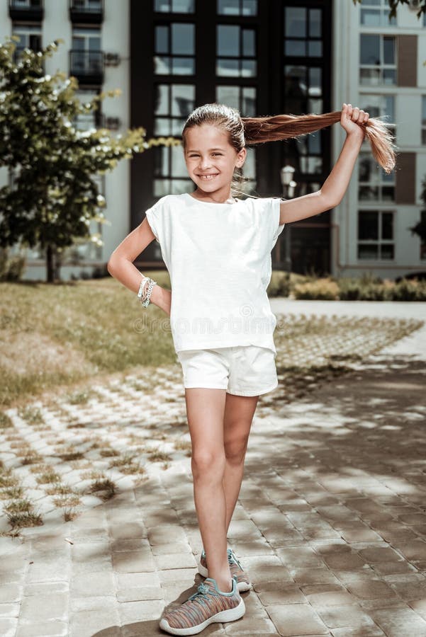 Leuk vrolijk positief meisje die haar paardestaart houden stock foto Leuk vrolijk positief meisje die haar paardestaart houden stock foto