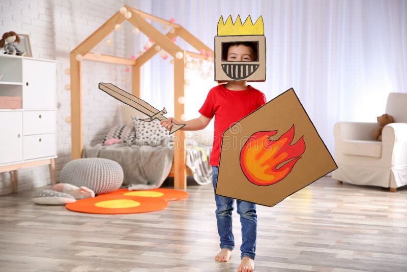 Leuk weinig jongen die met kartonpantser spelen stock foto's Leuk weinig jongen die met kartonpantser spelen stock foto's