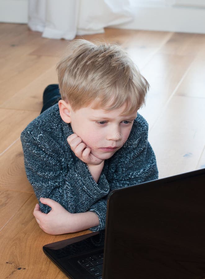 Leuk weinig jongen die op de vloer liggen die laptop met behulp van stock foto's Leuk weinig jongen die op de vloer liggen die laptop met behulp van stock foto's