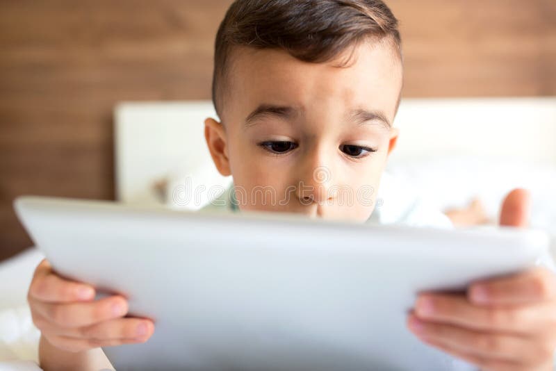 Leuk weinig jongen die zijn tablet gebruiken royalty-vrije stock foto's Leuk weinig jongen die zijn tablet gebruiken royalty-vrije stock foto's
