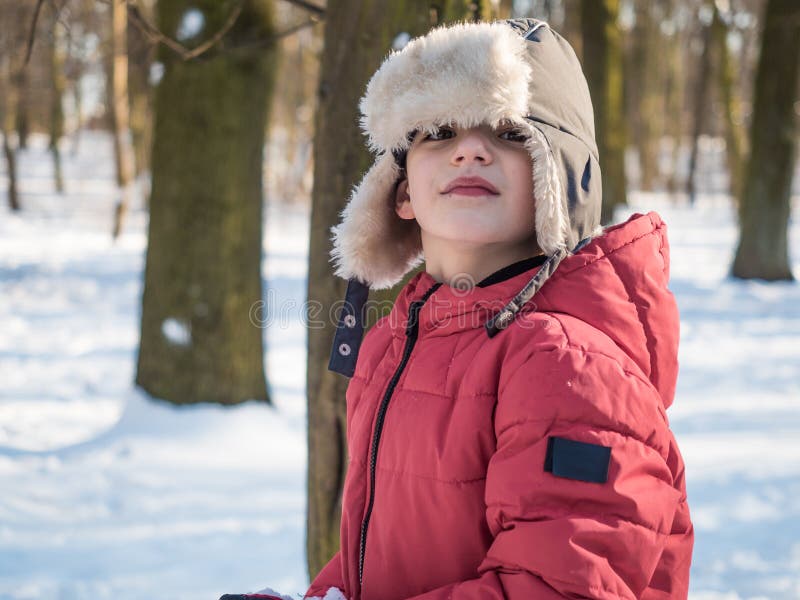 Leuk weinig jongen in rood jasje bij de achtergrond van het de winterpark stock afbeeldingen Leuk weinig jongen in rood jasje bij de achtergrond van het de winterpark stock afbeeldingen