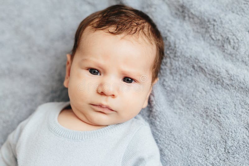 Leuke baby die ernstig de camera op een blauwe achtergrond bekijken stock fotografie Leuke baby die ernstig de camera op een blauwe achtergrond bekijken stock fotografie