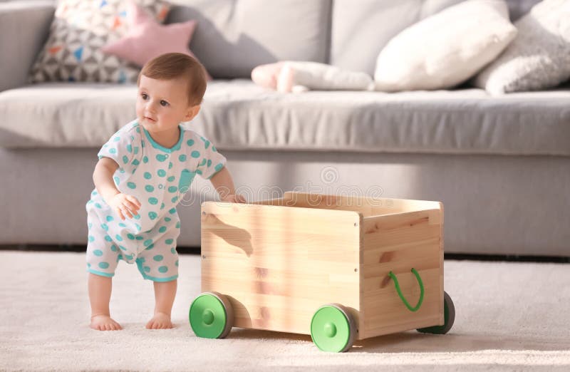 Leuke baby die op houten kar in woonkamer houden stock afbeelding Leuke baby die op houten kar in woonkamer houden stock afbeelding