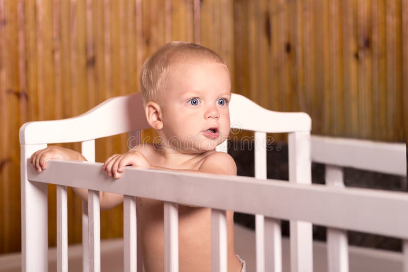 Leuke baby die zich in een wit bed bevinden Kinderdagverblijf voor jonge kinderen in het buitenhuis Weinig jongen die zich in zij royalty-vrije stock foto's Leuke baby die zich in een wit bed bevinden Kinderdagverblijf voor jonge kinderen in het buitenhuis Weinig jongen die zich in zij royalty-vrije stock foto's