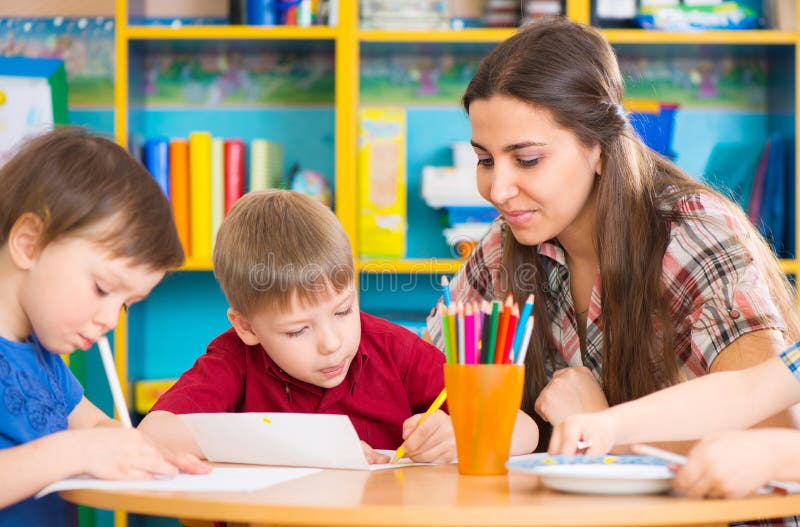 Leuke kinderen die met leraar bij peuterklasse trekken stock afbeeldingen Leuke kinderen die met leraar bij peuterklasse trekken stock afbeeldingen