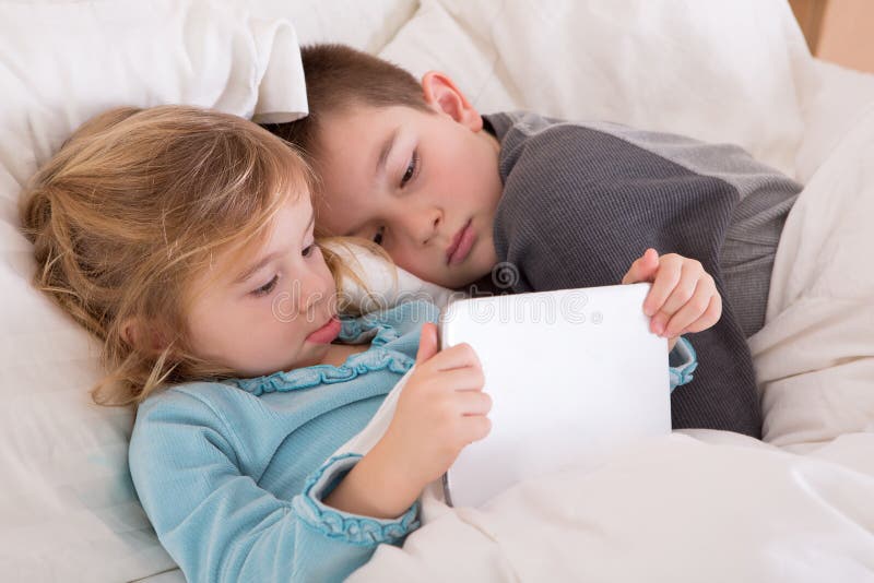 Leuke meisje en jongen die een bedtijdverhaal lezen stock foto's Leuke meisje en jongen die een bedtijdverhaal lezen stock foto's