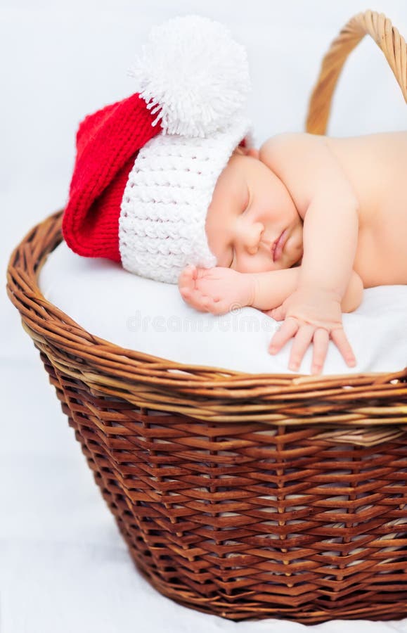 Leuke pasgeboren baby die Santa Claus-hoedenslaap in mand dragen stock foto Leuke pasgeboren baby die Santa Claus-hoedenslaap in mand dragen stock foto