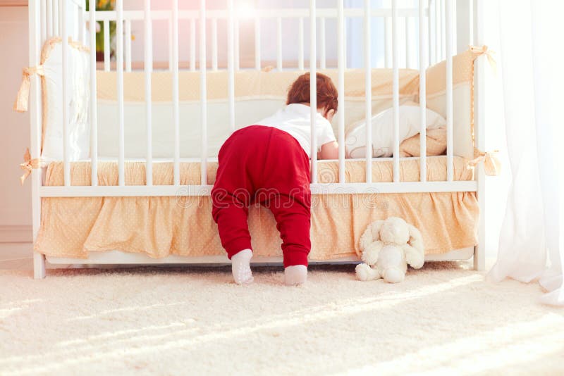 Leuke peuterbaby die in de wieg in kinderdagverblijfruimte thuis beklimmen royalty-vrije stock foto's Leuke peuterbaby die in de wieg in kinderdagverblijfruimte thuis beklimmen royalty-vrije stock foto's