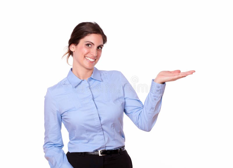 A portrait of a cute woman on blue shirt holding out her left hand while looking and smiling at you on isolated background - copyspace. A portrait of a cute woman on blue shirt holding out her left hand while looking and smiling at you on isolated background - copyspace