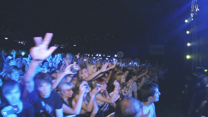 Leute beeinflussen Hände auf Lebendgesteinkonzert im Nachtklub Band, das am Stadium durchführt scheinwerfer