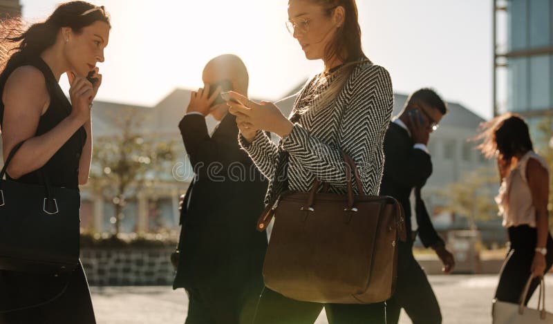 Leute beschäftigt unter Verwendung des Handys beim Gehen auf Straße zum Büro