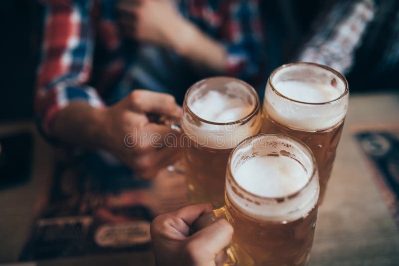 Leute-, Mann-, Freizeit-, Freundschafts- und Feierkonzept - glückliche männliche Freunde, die Bier trinken und Gläser an der Bar