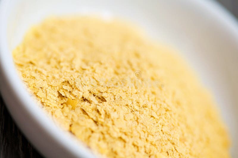 Nutritional yeast in a white bowl ready to add to a recipe. High in B vitamins and protein. Nutritional yeast in a white bowl ready to add to a recipe. High in B vitamins and protein.