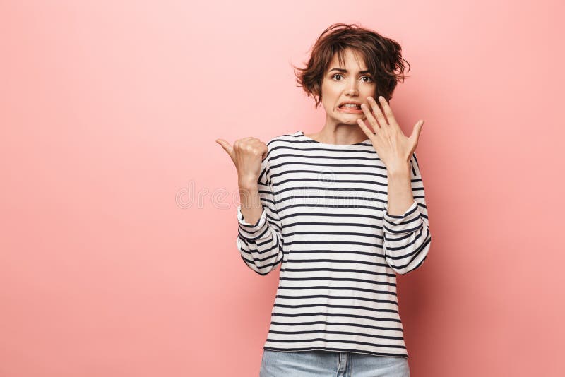 Levantamento bonito chocado confuso da mulher isolado sobre apontar cor-de-rosa do fundo da parede fotografia de stock Levantamento bonito chocado confuso da mulher isolado sobre apontar cor-de-rosa do fundo da parede fotografia de stock