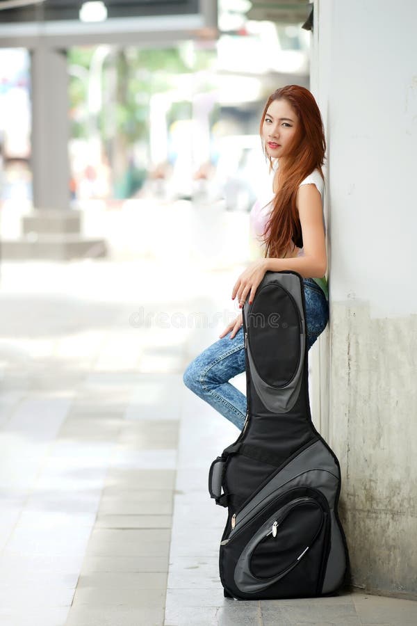Levantamento bonito novo da mulher exterior com seu saco da atuação da guitarra imagem de stock royalty free Levantamento bonito novo da mulher exterior com seu saco da atuação da guitarra imagem de stock royalty free