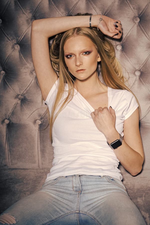 Levantamento modelo da mulher da forma O modelo de forma relaxa no sofá, estilo Mulher no tshirt e nas calças de brim, forma Mulh fotografia de stock royalty free Levantamento modelo da mulher da forma O modelo de forma relaxa no sofá, estilo Mulher no tshirt e nas calças de brim, forma Mulh fotografia de stock royalty free