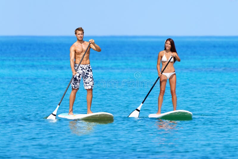Levante-se povos da praia do paddleboard na placa de pá imagem de stock royalty free Levante-se povos da praia do paddleboard na placa de pá imagem de stock royalty free