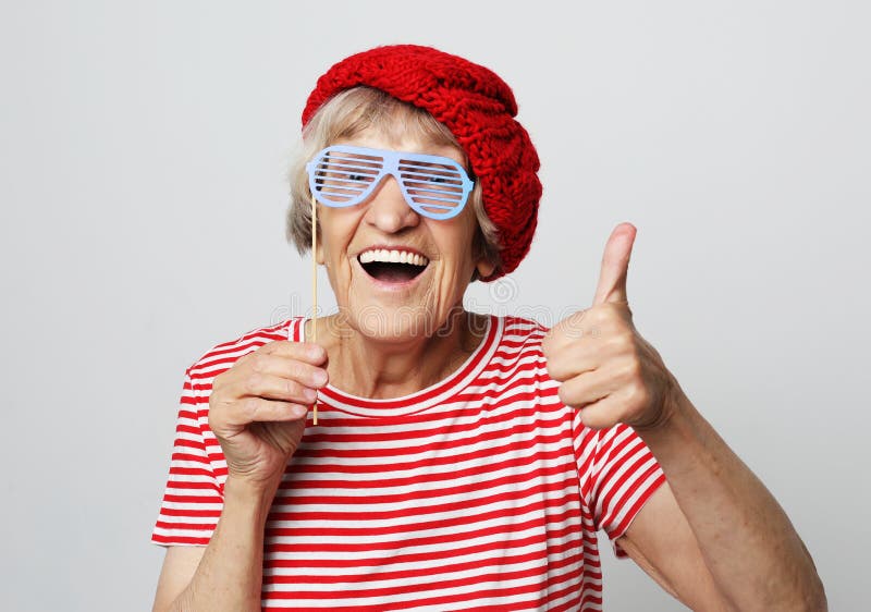Levensstijl, emotie en mensenconcept: grappige grootmoeder met valse glazen, lach en klaar voor partij