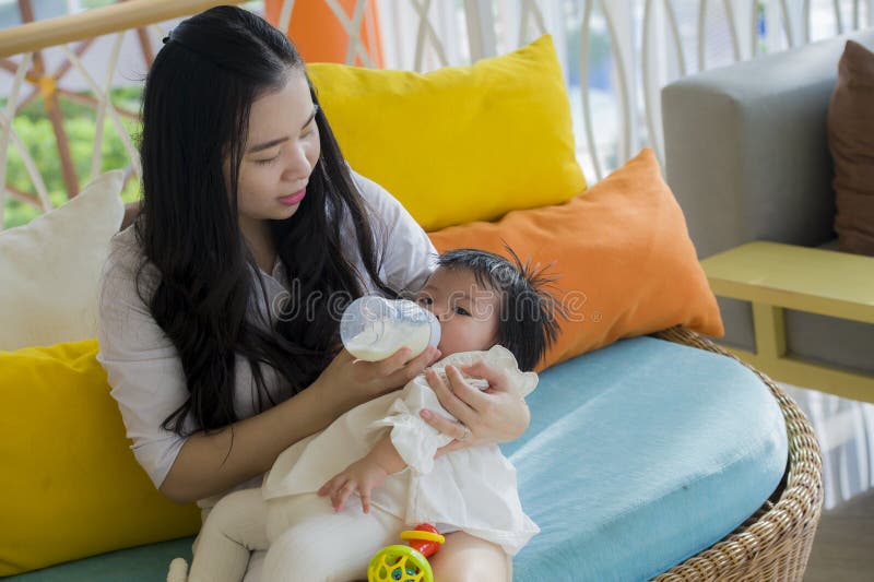 Levensstijl spontaan portret van jonge gelukkige en zoete Aziatische Chinese vrouw die haar mooi babymeisje met formulefles voede royalty-vrije stock afbeelding Levensstijl spontaan portret van jonge gelukkige en zoete Aziatische Chinese vrouw die haar mooi babymeisje met formulefles voede royalty-vrije stock afbeelding