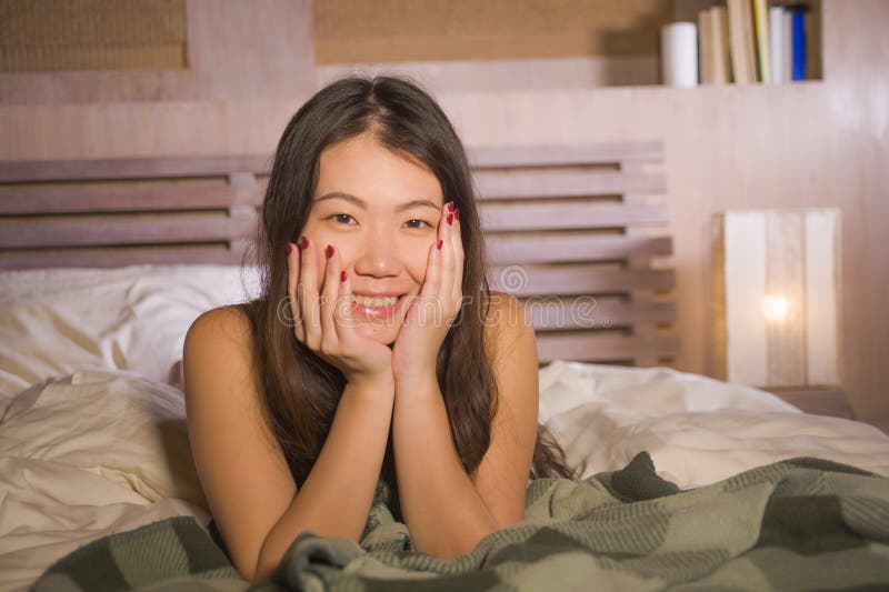 Levensstijlportret die van jonge mooie en gelukkige Aziatische Chinese vrouw in bed thuis slaapkamer liggen die vrolijke en ontsp stock fotografie Levensstijlportret die van jonge mooie en gelukkige Aziatische Chinese vrouw in bed thuis slaapkamer liggen die vrolijke en ontsp stock fotografie