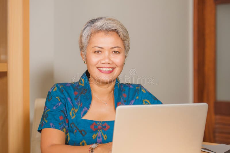 Levensstijlportret van het Gelukkige en aantrekkelijke elegante midden oude Aziatische bedrijfsvrouw werken die bij het bureau va royalty-vrije stock fotografie Levensstijlportret van het Gelukkige en aantrekkelijke elegante midden oude Aziatische bedrijfsvrouw werken die bij het bureau va royalty-vrije stock fotografie