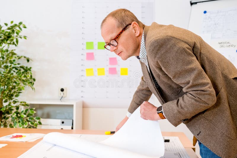 Leverantör som analyserar plan på ritning på arbetsplatsen royaltyfri foto Leverantör som analyserar plan på ritning på arbetsplatsen royaltyfri foto