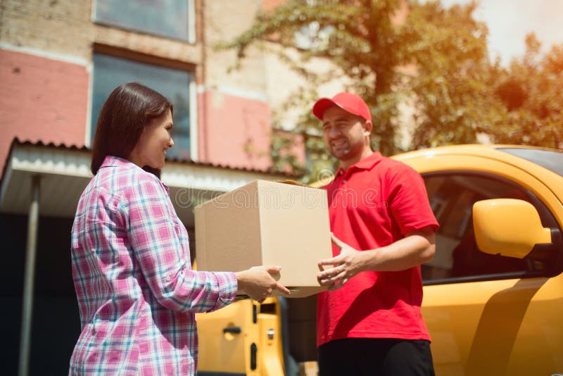 Man giving women big delivery box. Cheerful delivery men handing big tan package to beautiful female customer. Man giving women big delivery box. Cheerful delivery men handing big tan package to beautiful female customer.