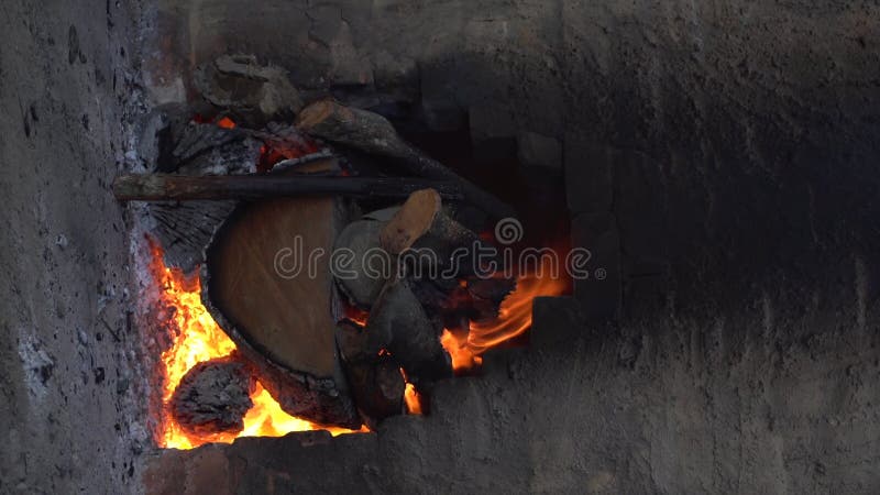 Leña ardiendo lentamente dentro de un horno de carbón vegetal.