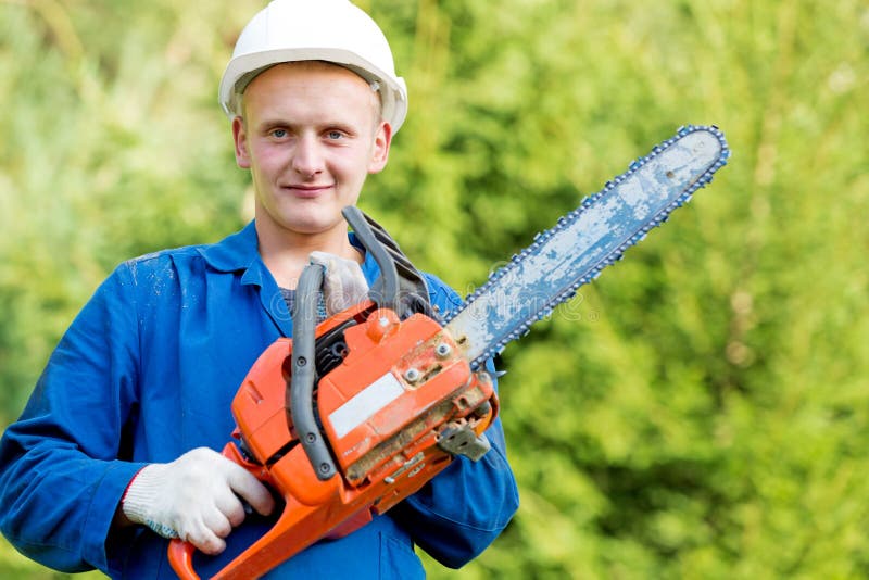 Leñador Worker con la motosierra en desgaste del trabajo en fondo del bosque imágenes de archivo libres de regalías Leñador Worker con la motosierra en desgaste del trabajo en fondo del bosque imágenes de archivo libres de regalías