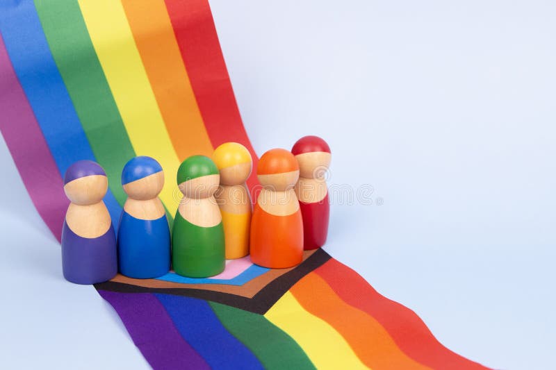 LGBT自豪感月份背景. LGBTQ彩虹旗上的人的小木塑. 多样性和包容性概念 免版税图库摄影