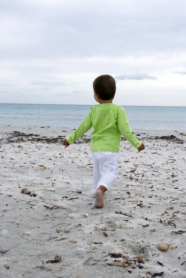 A little boy running and raising his hands on the beach portraying the feeling of freedom. A little boy running and raising his hands on the beach portraying the feeling of freedom