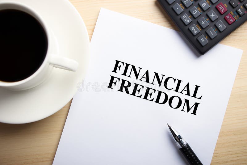 Text Financial Freedom is on the white paper with coffee, calculator and ball pen aside. Text Financial Freedom is on the white paper with coffee, calculator and ball pen aside.