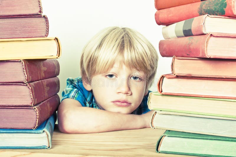 Bored kid sat in the library at school. Boring kid white stock images, royalty-free photos and pictures