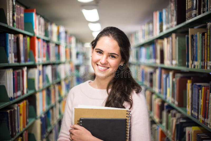In the library - pretty female student with books working in a h royalty free stock photo In the library - pretty female student with books working in a h royalty free stock photo