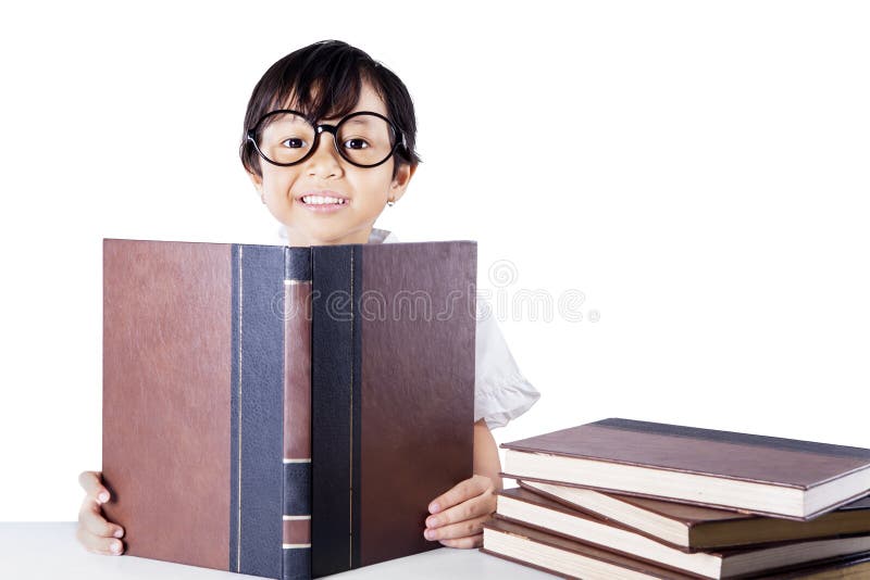 Cute elementary school student wearing glasses and reading textbooks on the table, isolated on white background. Cute elementary school student wearing glasses and reading textbooks on the table, isolated on white background