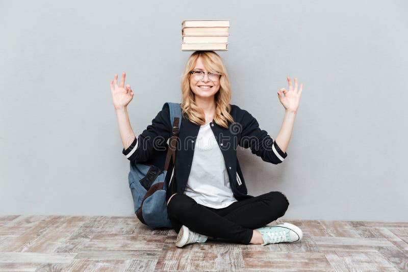 Libri felici della tenuta dello studente della giovane donna sulla testa immagini stock Libri felici della tenuta dello studente della giovane donna sulla testa immagini stock