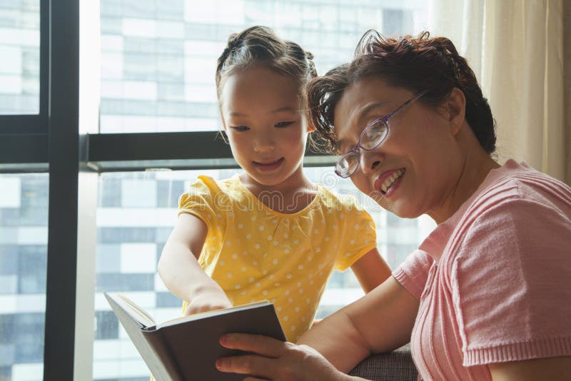 Libro de lectura de la abuela a su nieta imagenes de archivo