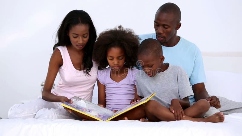 Libro de lectura de la familia en cama