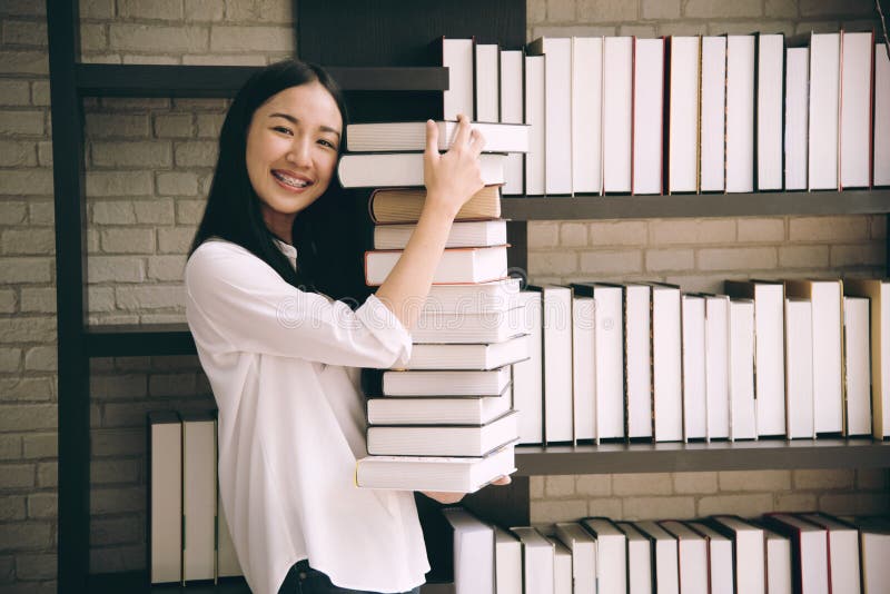 Libro della tenuta della studentessa dell'Asia a scuola di biblioteconomia immagine stock libera da diritti Libro della tenuta della studentessa dell'Asia a scuola di biblioteconomia immagine stock libera da diritti