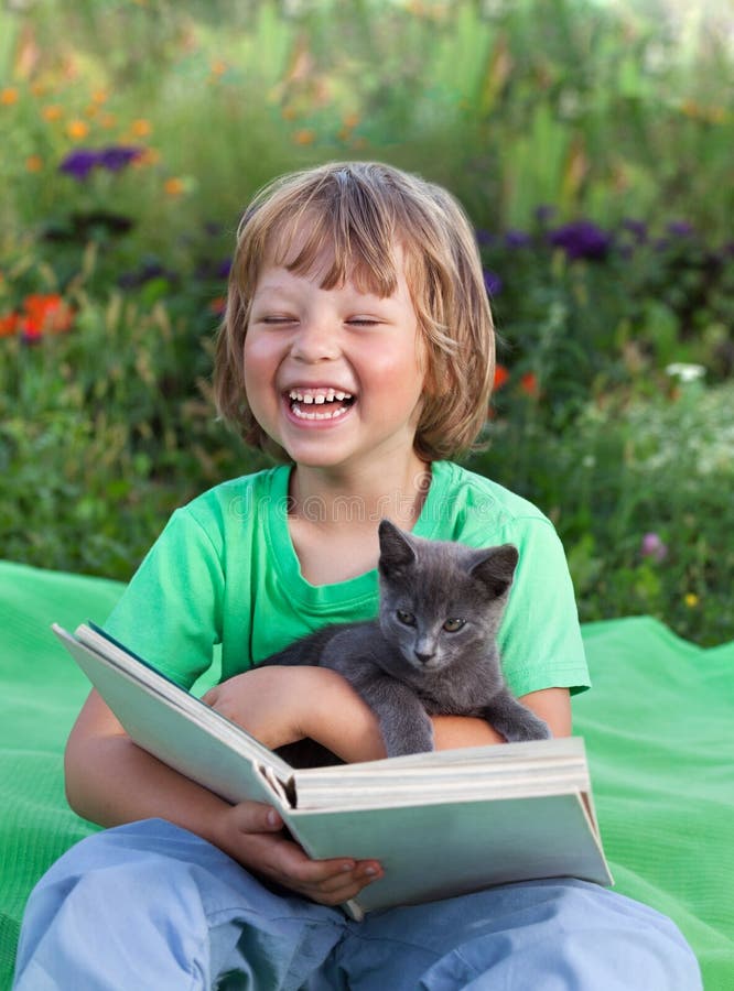 Libro di lettura del ragazzo con il gattino nell'iarda, bambino con la lettura dell'animale domestico fotografia stock libera da diritti Libro di lettura del ragazzo con il gattino nell'iarda, bambino con la lettura dell'animale domestico fotografia stock libera da diritti