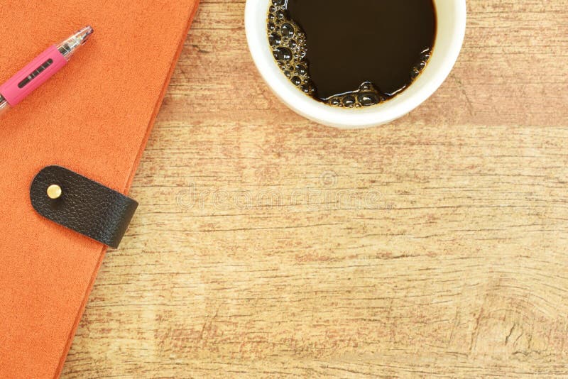 Libro e penna del diario con la tazza di caffè nero sulla tavola di legno
