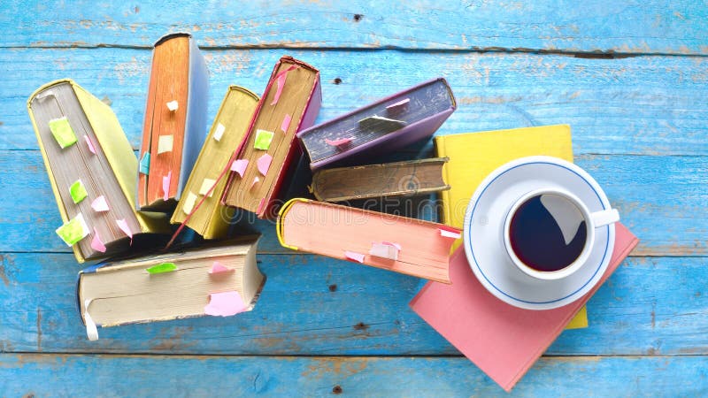 Libros multicolores, taza de café, piso sobre un viejo escritorio de madera, lectura, educación, literatura, aprendizaje