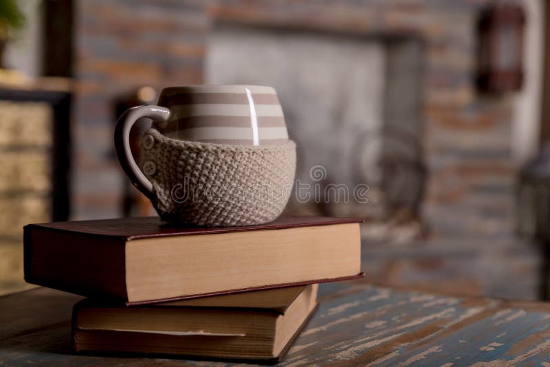 Libros viejos y taza de café en la tabla de madera del grunge sobre fondo de la chimenea Composición con la pila de libros y de t fotos de archivo Libros viejos y taza de café en la tabla de madera del grunge sobre fondo de la chimenea Composición con la pila de libros y de t fotos de archivo