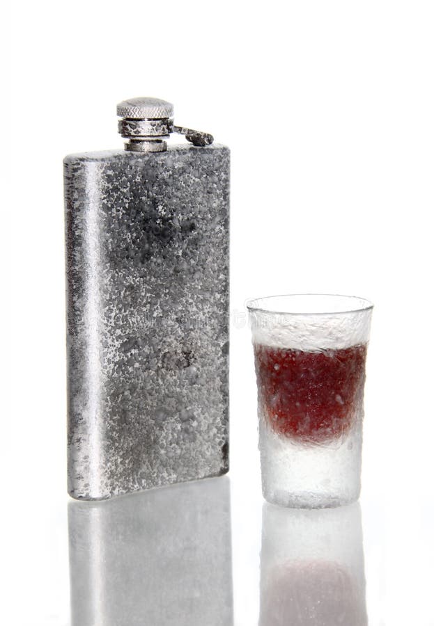 A frozen hip flask and a frozen glass of ice cold liquor. A frozen hip flask and a frozen glass of ice cold liquor.