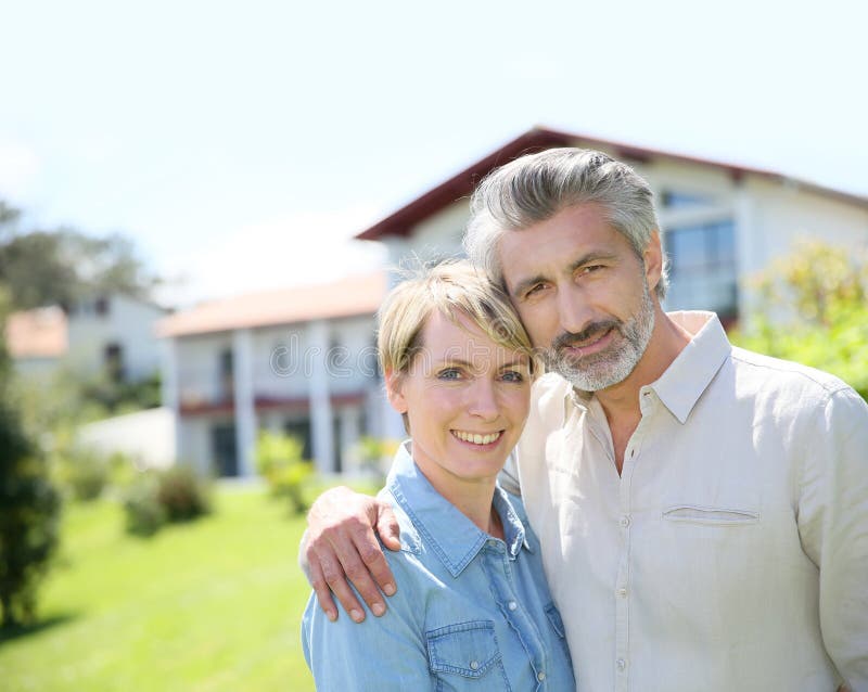 Liddle-aged couple standing on front of the house