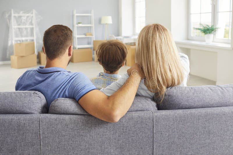 Liebend enge glückliche Familie Sitzsofa hinten Aussicht im neuen Wohnzimmer Mutter Vater und kleiner Sohn stockfotografie