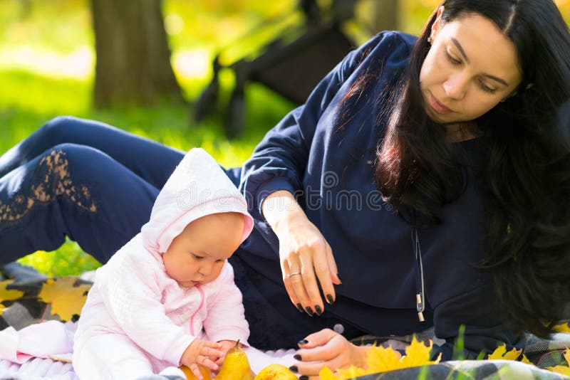 Liebende junge Mutter, die ihre Babytochter aufpasst lizenzfreie stockfotografie Liebende junge Mutter, die ihre Babytochter aufpasst lizenzfreie stockfotografie