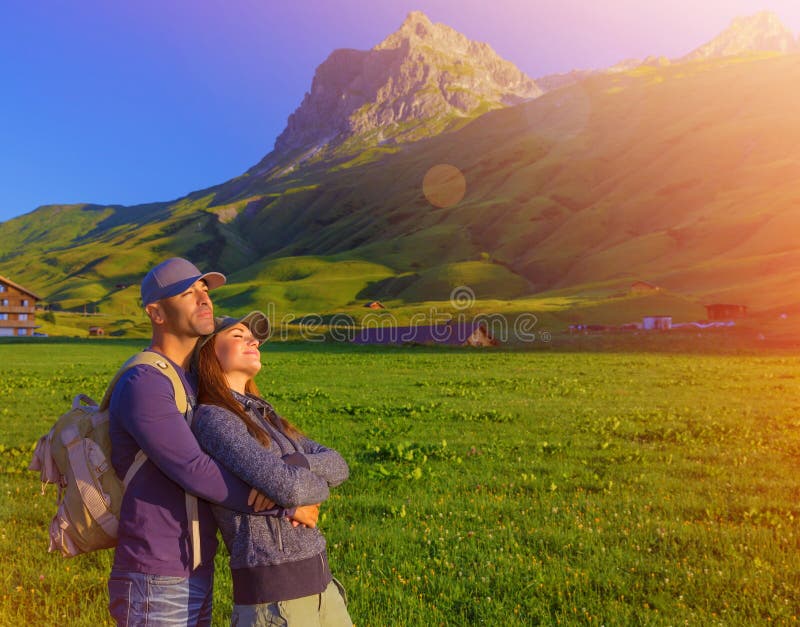 Liebevolle Paare, die Sonnenuntergang in den Bergen genießen stockfoto Liebevolle Paare, die Sonnenuntergang in den Bergen genießen stockfoto