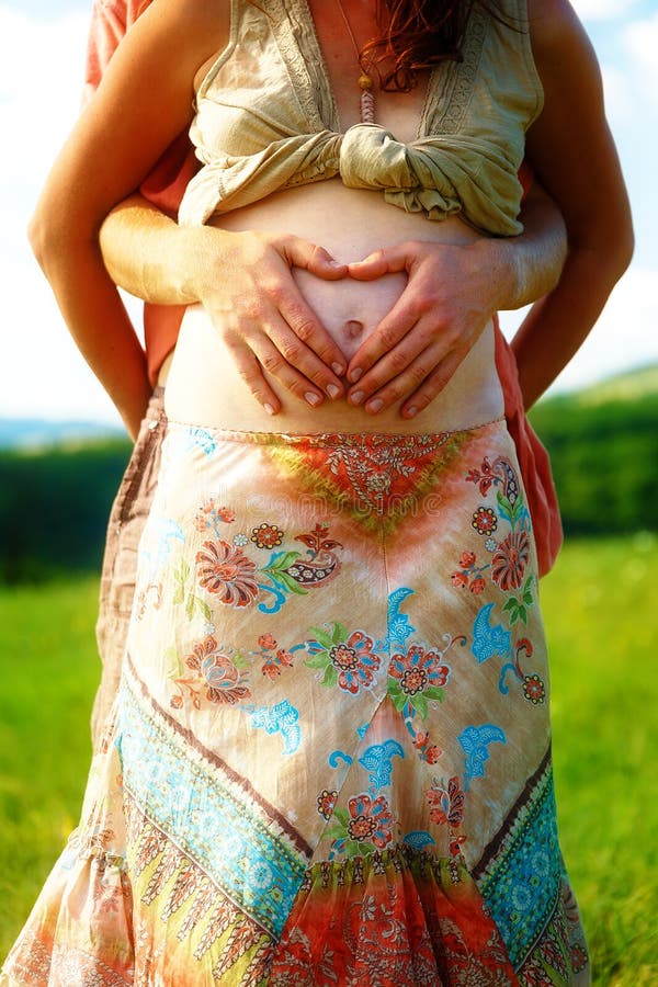 Liebevolles schönes ethno Paar, Mann macht die Herzform auf ihrem schwangeren Bauch stockfotografie Liebevolles schönes ethno Paar, Mann macht die Herzform auf ihrem schwangeren Bauch stockfotografie