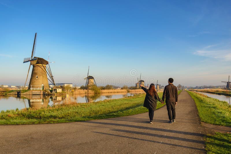 Liefdepaar die met Nederlandse Windmolen bij Kinderdijk-Dorp lopen royalty-vrije stock fotografie Liefdepaar die met Nederlandse Windmolen bij Kinderdijk-Dorp lopen royalty-vrije stock fotografie